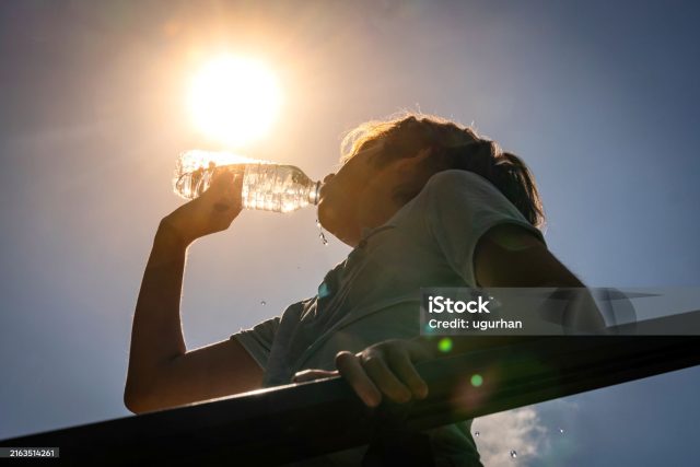 Boy drinking water from a bottle on a sunny hot day.